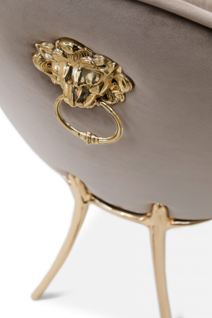 A cream, nude modern dining chair with the leon symbol in the back of the chair and gold details.