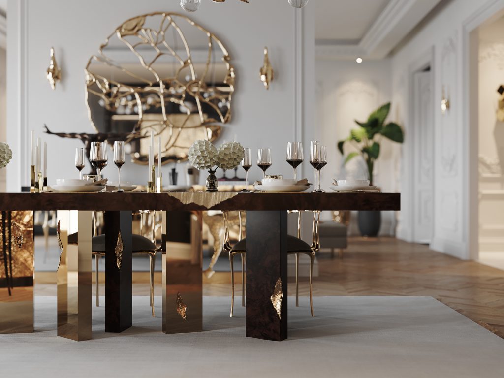 Luxury Dining Table- Luxury Dining Table - modern dining room, white walls, plants, round mirror with gold details and a brown dining table with gold details, with glasses, plates and decorative candles and black and gold chairs